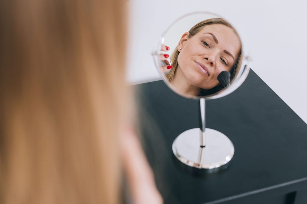 Errores al maquillarte que envejecen - Mujer mirándose al espejo